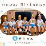 8月のお誕生会で、金色の冠をかぶった園児たちが誕生日カードを手に記念撮影する様子