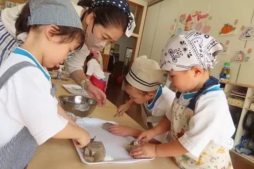 エプロンと三角巾を着けて調理体験をするあざみ野こども園の子どもたち