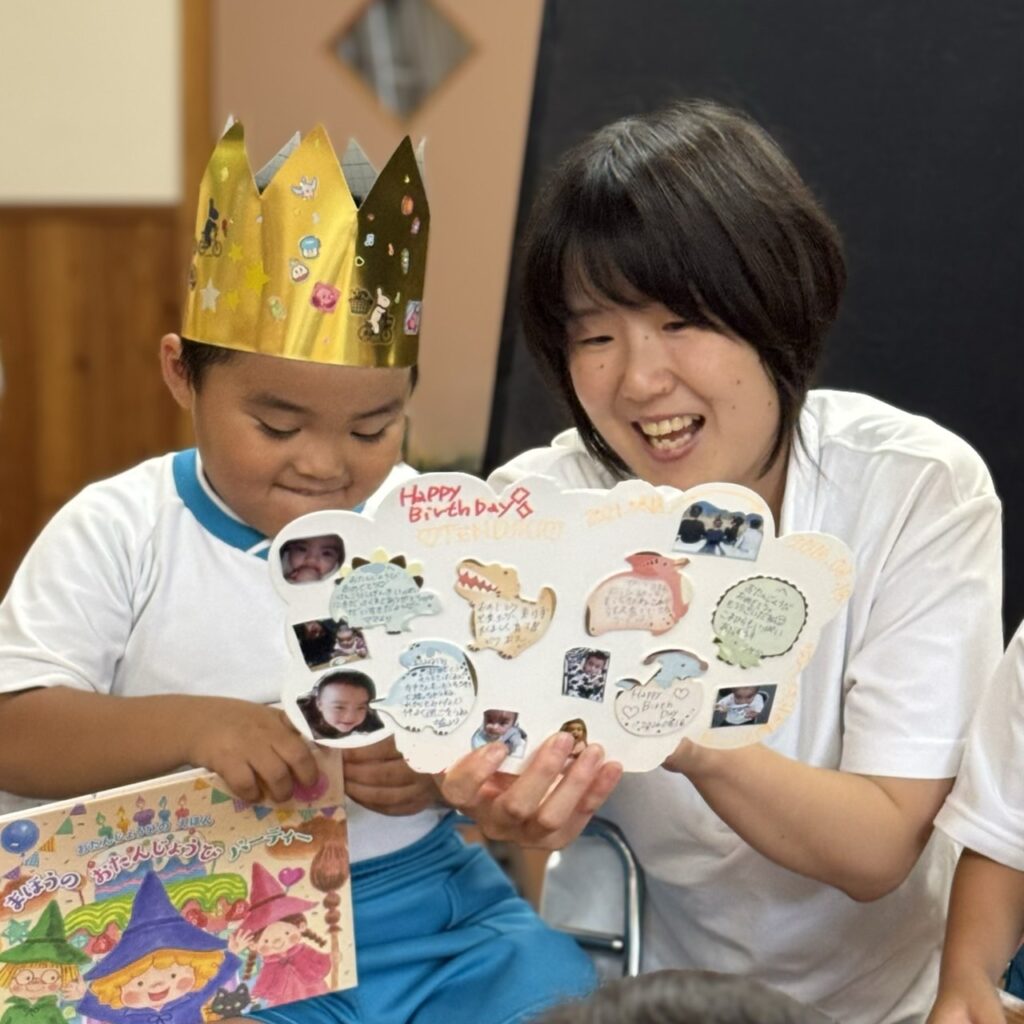 あざみ野こども園の誕生日会で、先生と一緒にバースデーカードを見る園児