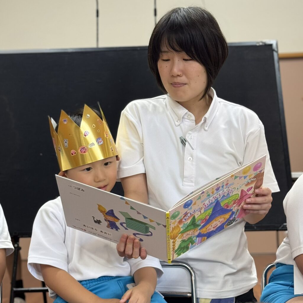 先生と一緒に誕生日の絵本を楽しむ園児